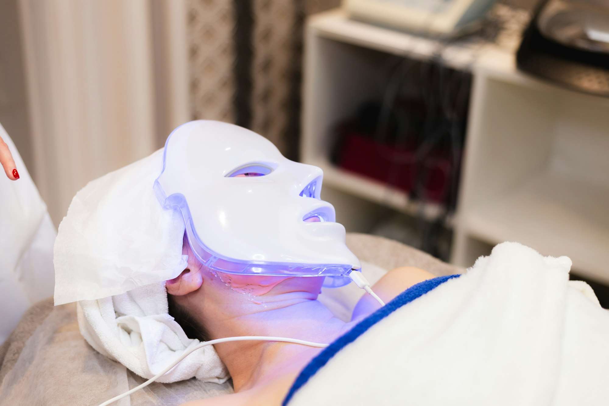 The client lies in the salon on the cosmetology table with a white mask on her face
